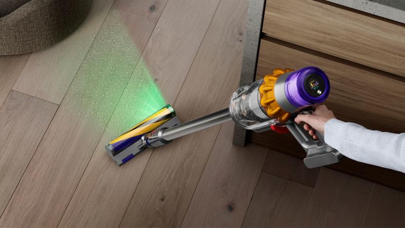 A Dyson V15 Detect cleaning a hardwood floor with its green light shining