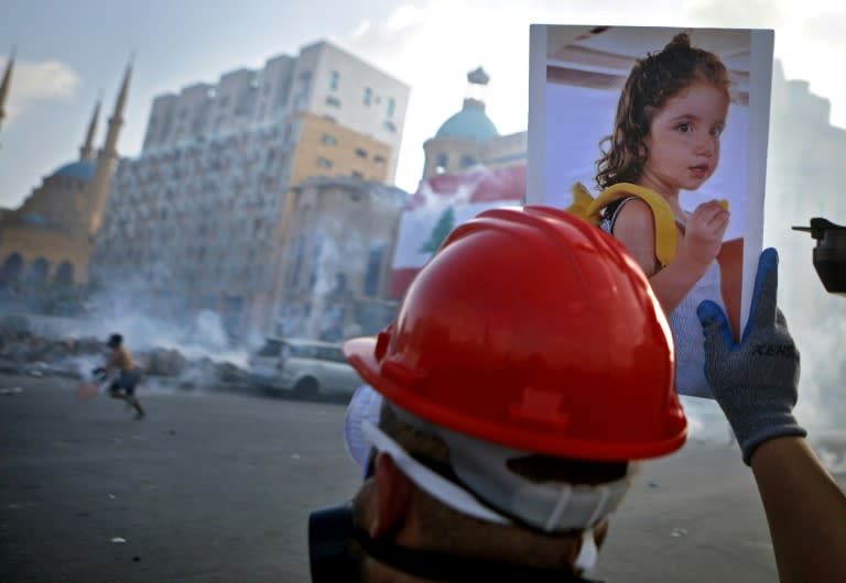 A Lebanese protester carries a photo of 3-year-old Alexandra Najjar, who was wounded in the port explosion and later succumbed to her wounds