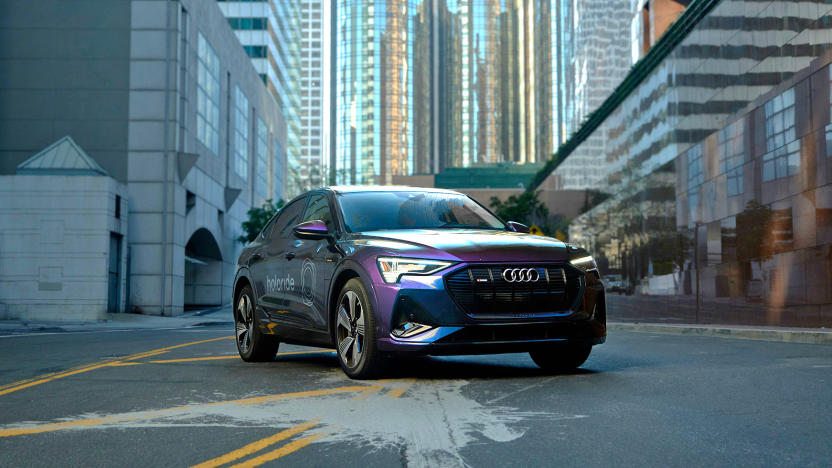 A Holoride VR experience test vehicle is photographed on a back street with buildings in the background.