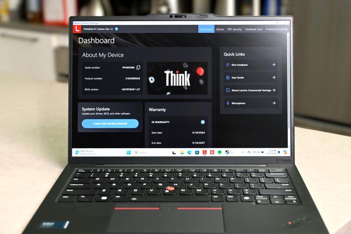 The Lenovo ThinkPad X1 Carbon (12th-gen) with its screen and keyboard facing the camera. On its display is Lenovo's Think dashboard showing information about the device, including system update and warranty.