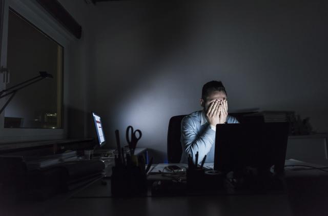 Exhausted businessman sitting at desk in office at night