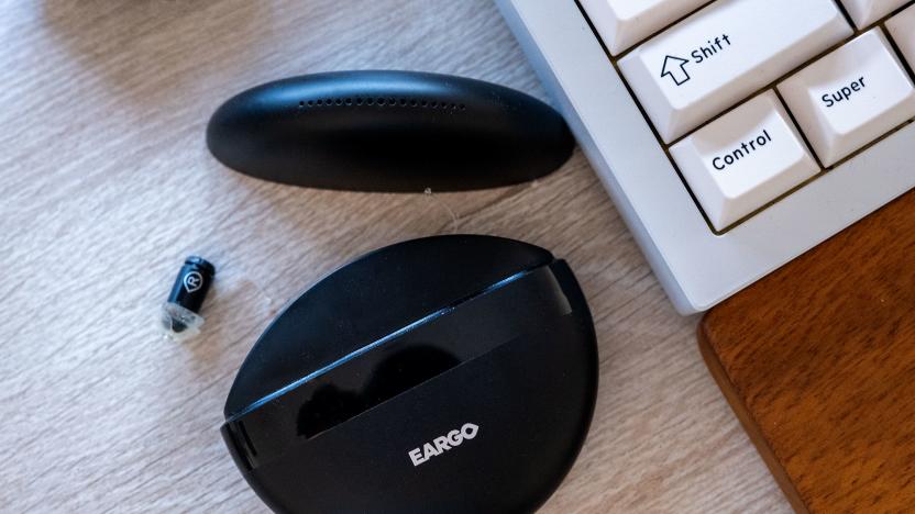 The Eargo hearing aids charging case is pictured open alongside one of the buds.