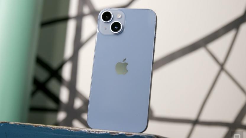 The blue iPhone 14 standing on a shelf with its dual rear cameras facing out.