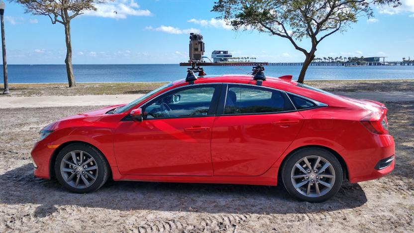 A red car parked on the sand near a waterfront has the new Google Street View camera system mounted on its roof.