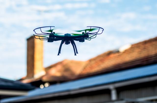 Drone quad copter flying over the roofs. Drone photography and videography. Toy drone flight. Copy space