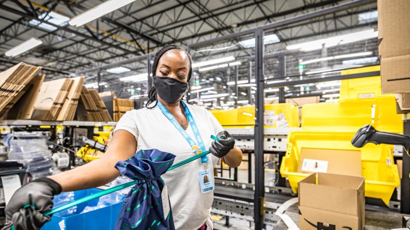 A woman packs an Amazon order. Amazon boxes with the company's arrow logo are scattered in the background.