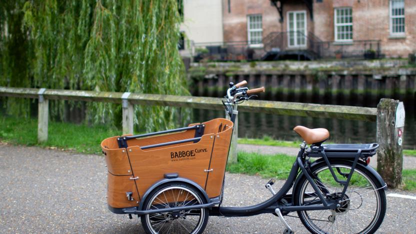 The Babboe Curve-E, Dutch-style electric cargo bike seen parked on a road next to a canal.