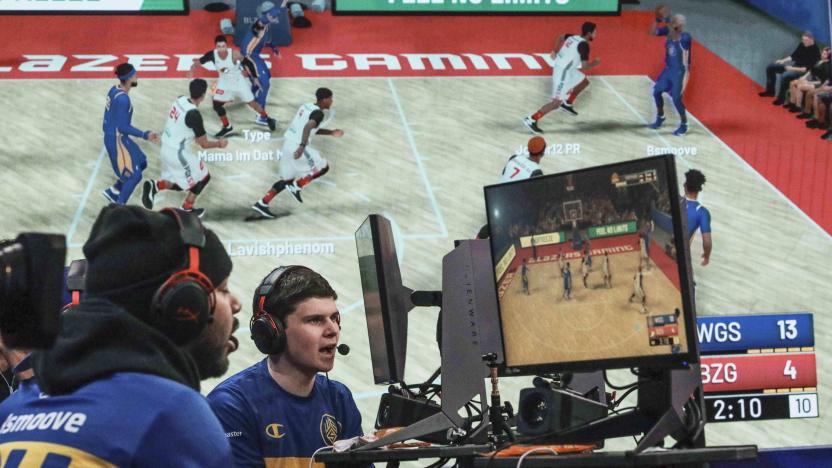 A giant monitor shows play as Warriors Gaming Squad teammates Charles "CB13" Bostwick, center, from New York, and his teammate Alexander Reese, left, from Milwaukie, Or., react to scoring during the NBA 2k League (NBA2KL) professional esports playoffs, Wednesday, July 24, 2019, in Queens borough of New York. The teams kicked off day one of the NBA2KL playoffs with Blazers on the losing 67-45. (AP Photo/Bebeto Matthews)