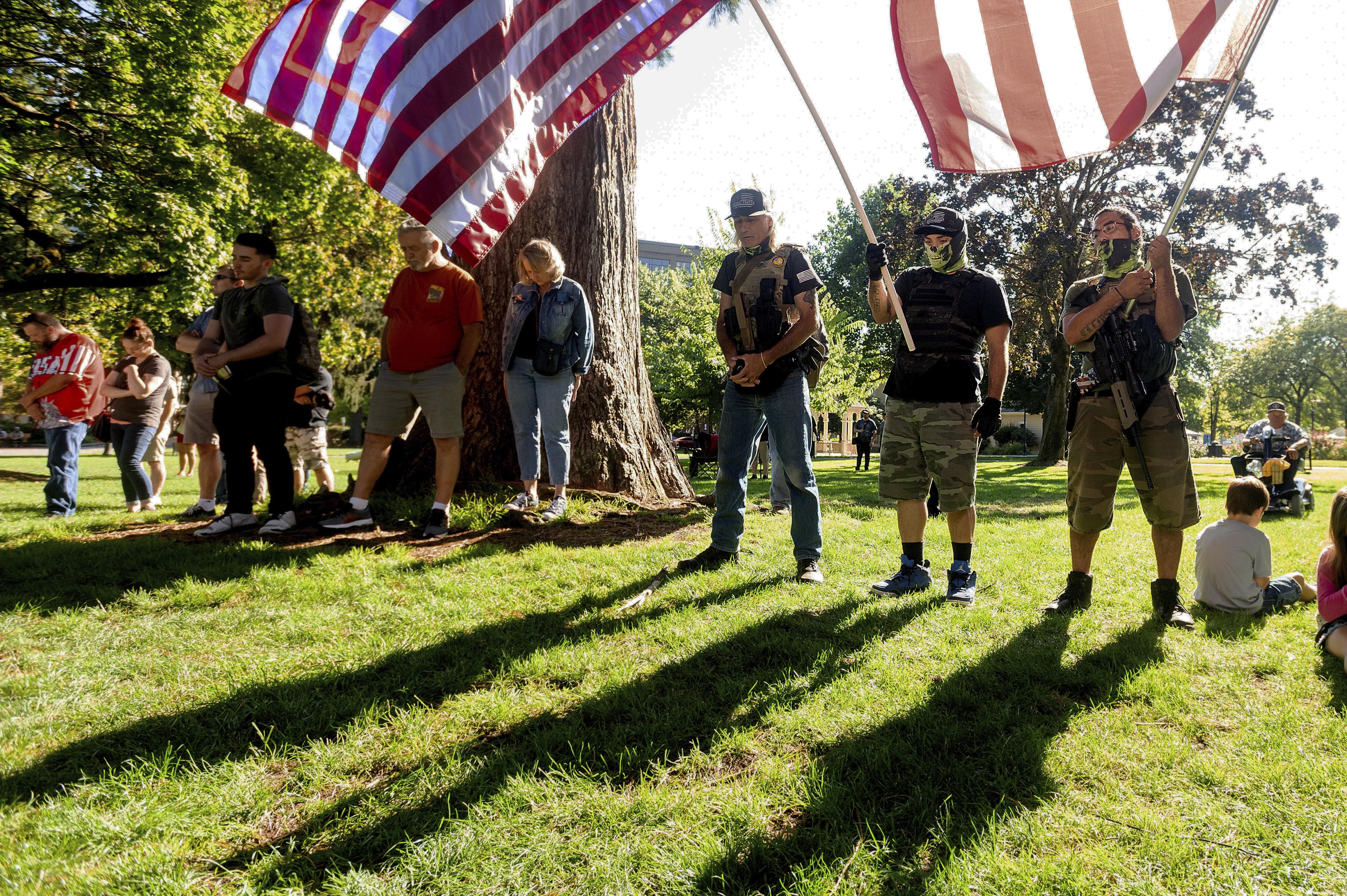 Mourners, who declined to give their names, listen to a prayer during a memorial for Aaron J. Danielson on Saturday, Sept. 5, 2020, in Vancouver, Wash. Danielson, a supporter of the conservative group Patriot Prayer, was fatally shot in August as supporters of President Donald Trump and Black Lives Matter protesters clashed in Portland, Ore. (AP Photo/Noah Berger)