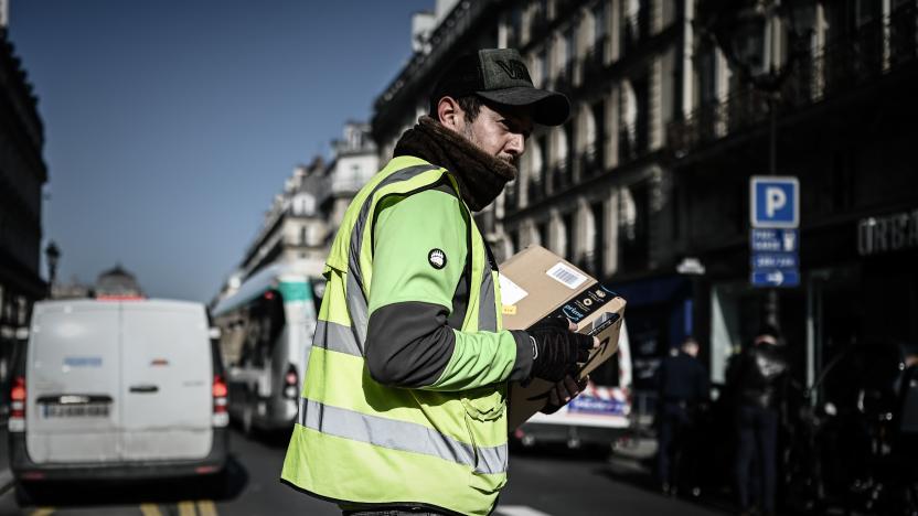 A man crosses a street as he delivers an Amazon parcel in Paris on March 19, 2020, on the third day of a strict lockdown in France to stop the spread of COVID-19, caused by the novel coronavirus. (Photo by PHILIPPE LOPEZ / AFP) (Photo by PHILIPPE LOPEZ/AFP via Getty Images)