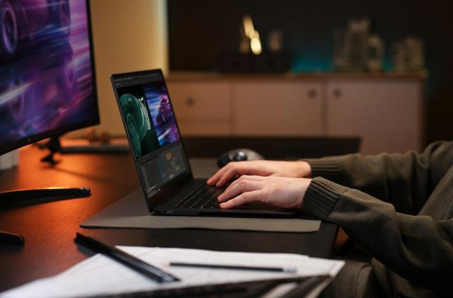 A pair of hands using a laptop on a desk. 