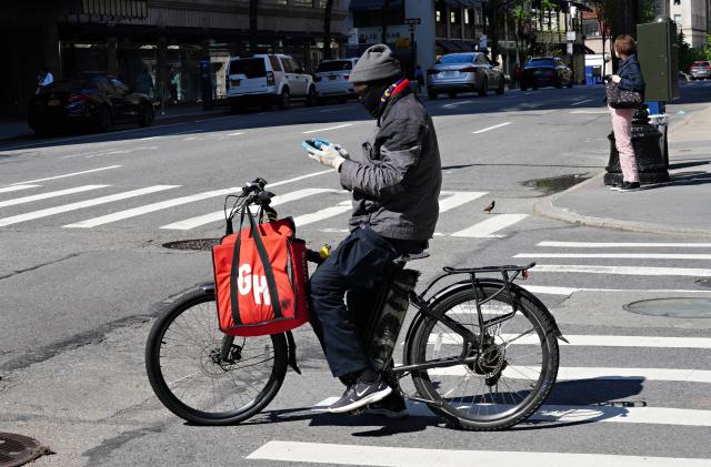 NEW YORK, NY - MAY 03: A Grubhub delivery person checks his phone during the coronavirus pandemic on May 3, 2020 in New York City. COVID-19 has spread to most countries around the world, claiming over 247,000 lives with over 3.5 million infections reported. (Photo by Cindy Ord/Getty Images)