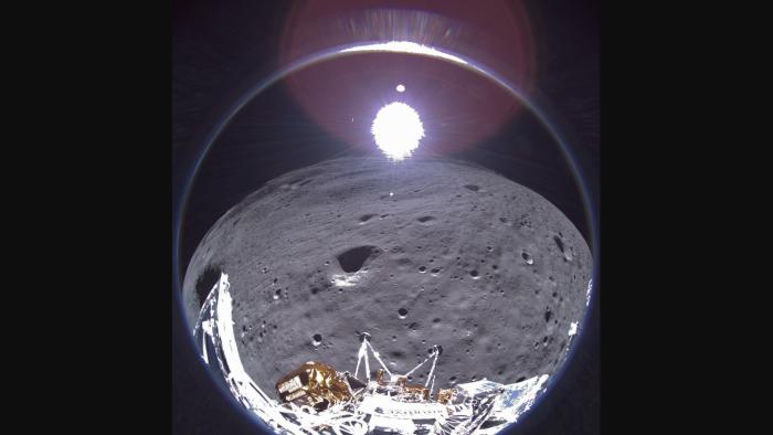 A wide angle view from the Odysseus moon lander showing a portion of the spacecraft, the moon, and Earth in the faraway distance
