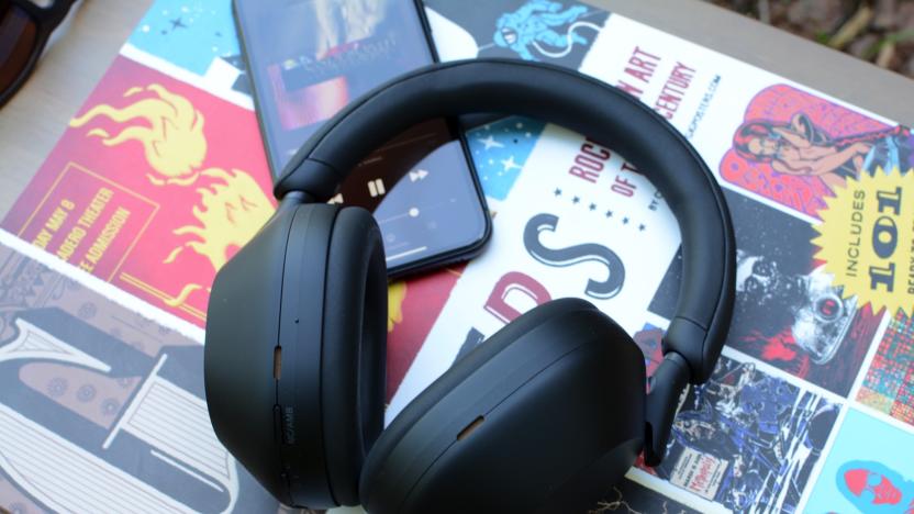 A pair of black headphones, the Sony WH-1000XM5, rest on top of a book and a smartphone.