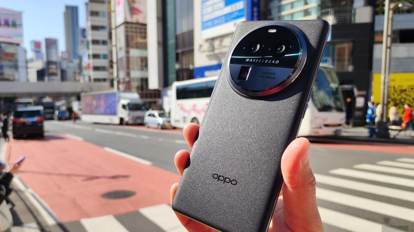 This image shows a hand holding the Oppo Find X6 Pro in front of a city street by a crosswalk.