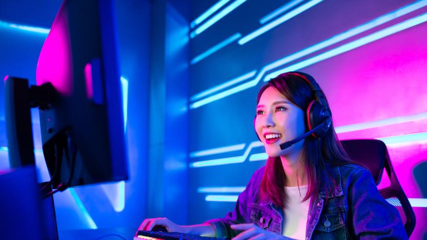 Young woman wearing a headset while sitting at a computer. The keyboard and backdrop are lit in neon colors.