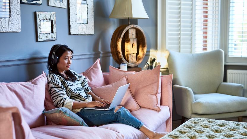 Vietnamese woman in her 30s sitting on sofa in living room, typing on computer, working from home, freelancing, communication