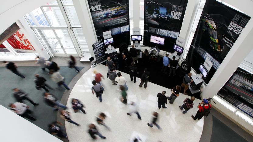 Visitors play the Electronic Arts' video game "Need for Speed Shift" as others make their way through the hallway during the Electronic Entertainment Expo or E3 in Los Angeles, June 3, 2009. The convention runs June 2-4. REUTERS/Danny Moloshok (UNITED STATES BUSINESS)