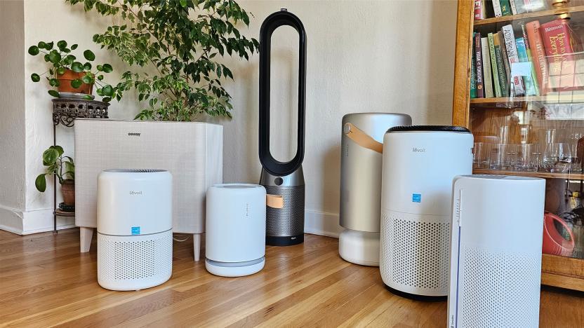 Air purifiers from Levoit, Molekule, Coway, Dyson and more sit on a wooden floor in a room with plants in it. 