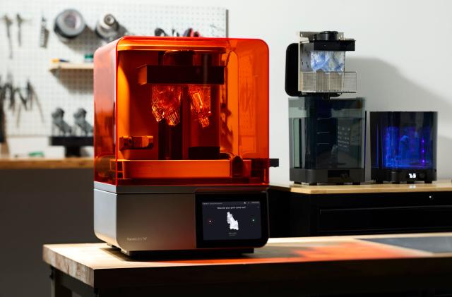 Image of the new Formlabs Form 4 3D printer on a workbench, with other Formlabs' accessories in the background and a pinboard with tools in the blur.