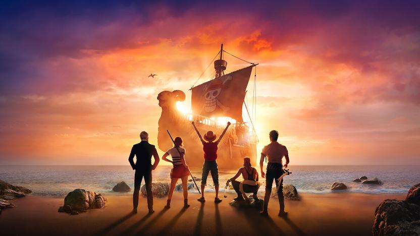 Promotional art for Netflix’s live-action ‘One Piece.’ Five crew members face a shoreline with their backs to us. In the center, Monkey D. Luffy (Iñaki Godoy) stands with his arms raised triumphantly. A pirate ship approaches on the seas in the background.