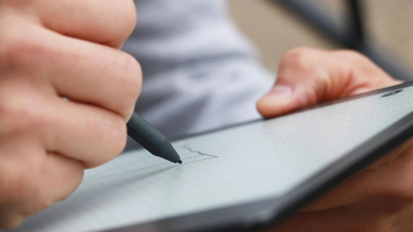 A person writing with a stylus on the Kindle Scribe e-reader / digital notebook. The photo is taken from the side.