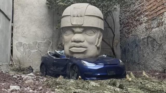¿Por qué hay una cabeza Olmeca aplastando un auto Tesla?