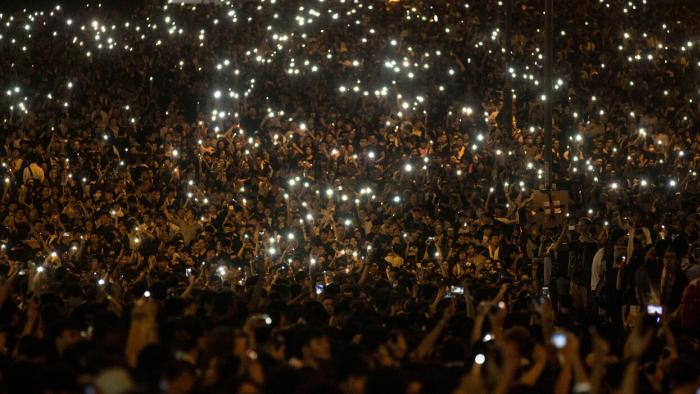 Nighttime shot of countless protestors holding up their phones’ flashlights.