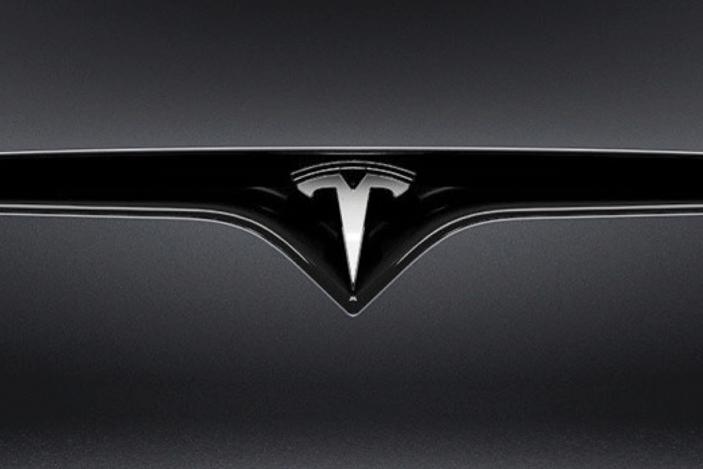 Closeup of a Tesla logo on a car.