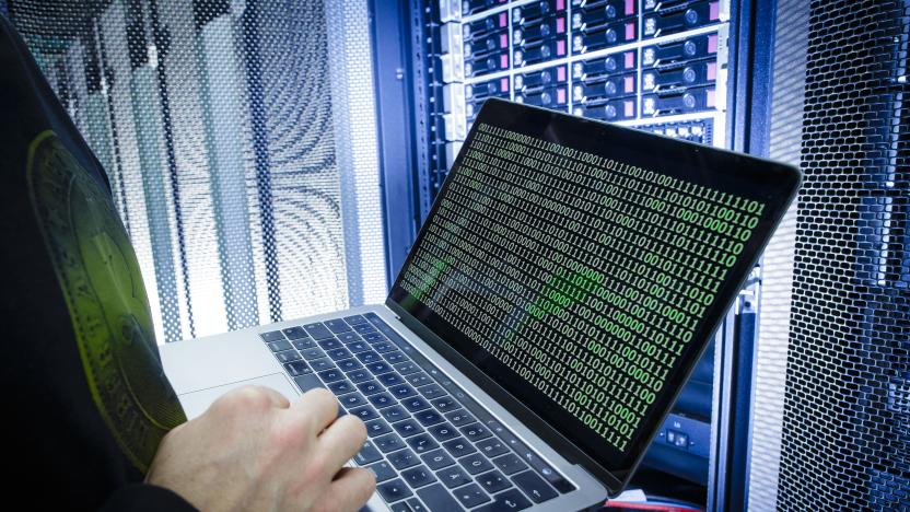 BERLIN, GERMANY - JANUARY 12: Symbolic photo with topic online crime, data theft and piracy: A man poses with a laptop showing a binary code in front of Server racks in a server center on January 12, 2018, in Berlin, Germany. (Photo Illustration by Thomas Trutschel/Photothek via Getty Images)