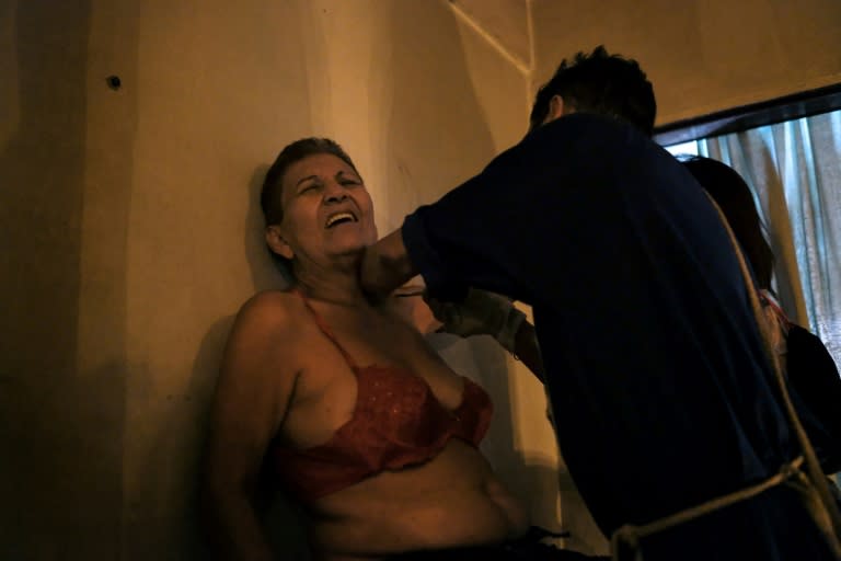 Rosa Saez, 77, is treated by spiritual healer Rosales at his clinic in Petare (AFP Photo/Matias Delacroix)