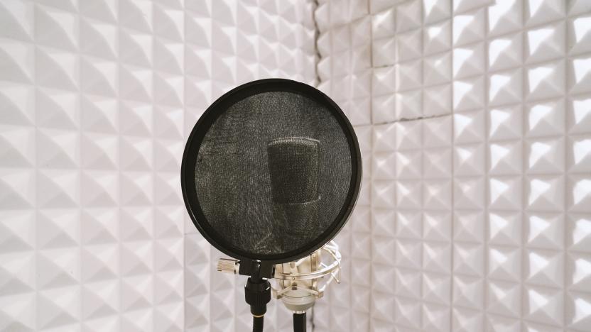 microphone with pop filter on mic stand in soundproof isolation booth for vocal recording at sound studio