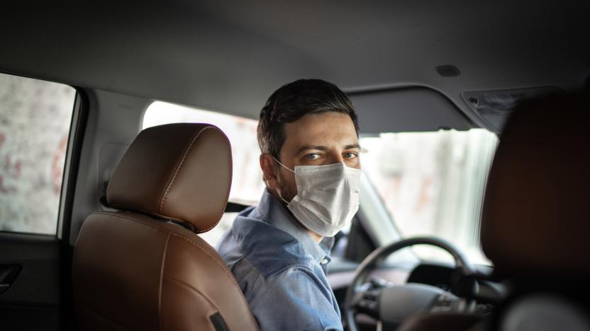 Driver taking to a passenger on seat back wearing protective medical mask