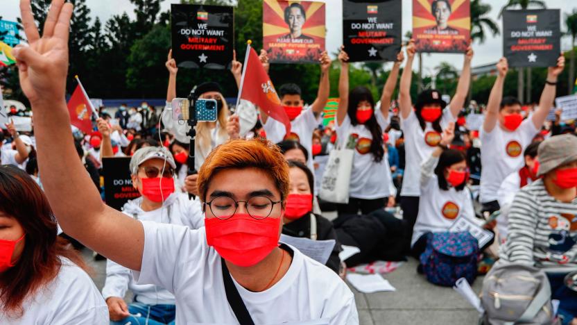 Burmese demonstrator holds a placard during an assembly to...