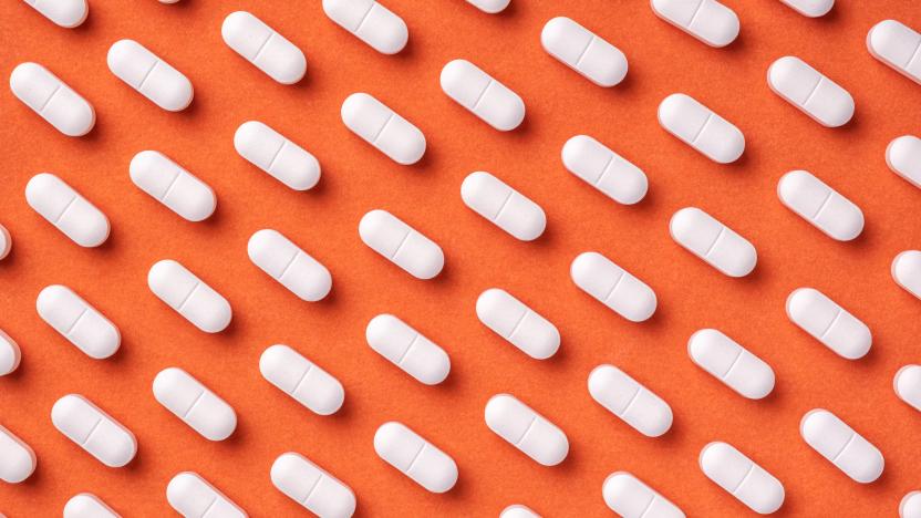 Orange and red medicine background with white pills and tablet, macro. Drug production backdrop. Medical pattern from vitamin capsule, closeup.