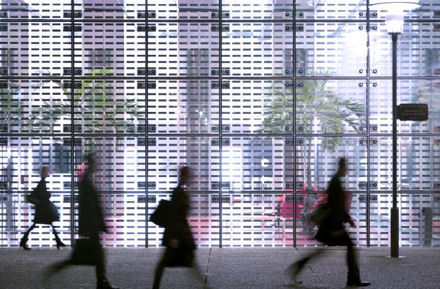 Businessmen and businesswomen passing front of modern office building.