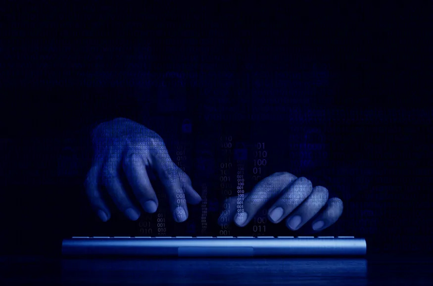 Cyberattack and internet crime, hacking and malware concepts. Digital binary code data numbers and secure lock icons on hacker' hands working with keyboard computer on dark blue tone background.