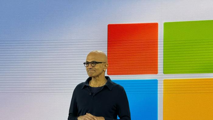 Microsoft’s Satya Nadella onstage in front of a Windows logo.