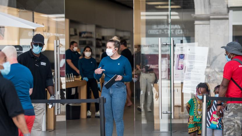 CHARLESTON, SC - MAY 13: An employee at the Apple Store helps a customer on May 13, 2020 in Charleston, South Carolina. Customers had their temperatures taken and were required to wear masks at the South Carolina store, as locations in Idaho, Alabama, and Alaska reopened as well following forced closures due to the coronavirus. (Photo by Sean Rayford/Getty Images)