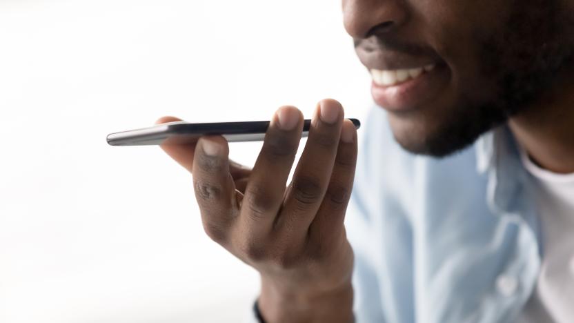 Close up of african American man hold modern smartphone talk using virtual digital assistant, smiling biracial male speak on cellphone on loudspeaker or record voice message, new technology concept