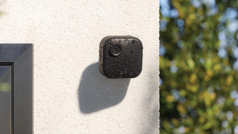 Image of Blink's Outdoor Camera 4, attached to a white rendered concrete wall covered in water droplets from a recent shower. 