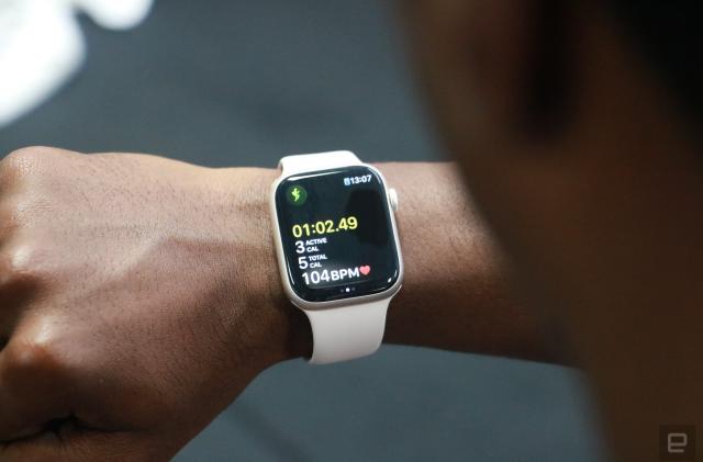 The Apple Watch Series 8 showing a workout tracking screen, on the wrist of a person looking at their watch in a gym.