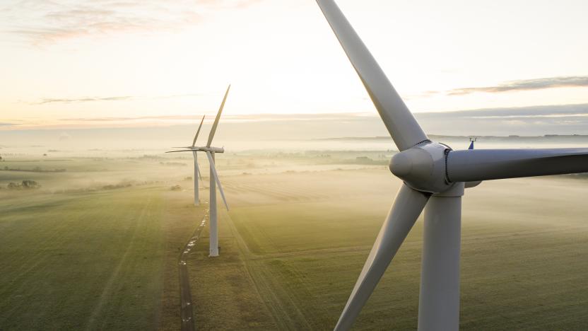 Aerial view of three wind turbines in the early morning fog at sunrise in the English countryside