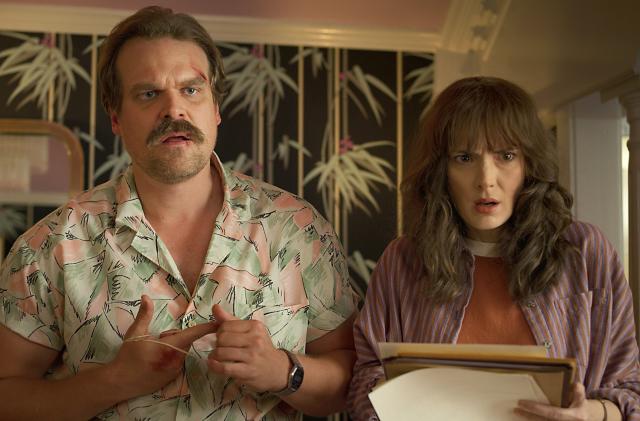 Jim Hopper (David Harbour) and Joyce Byers (Winona Ryder) in Stranger Things. Hopper has cuts on his face and both characters have their mouths open as if they're dumbfounded.