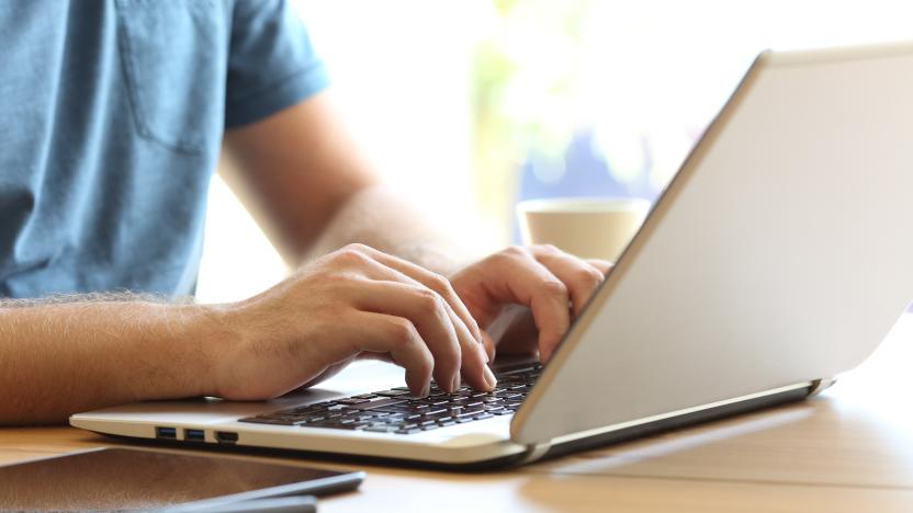 Close up of man hands typing on a laptop keyboard on a desk at home or office