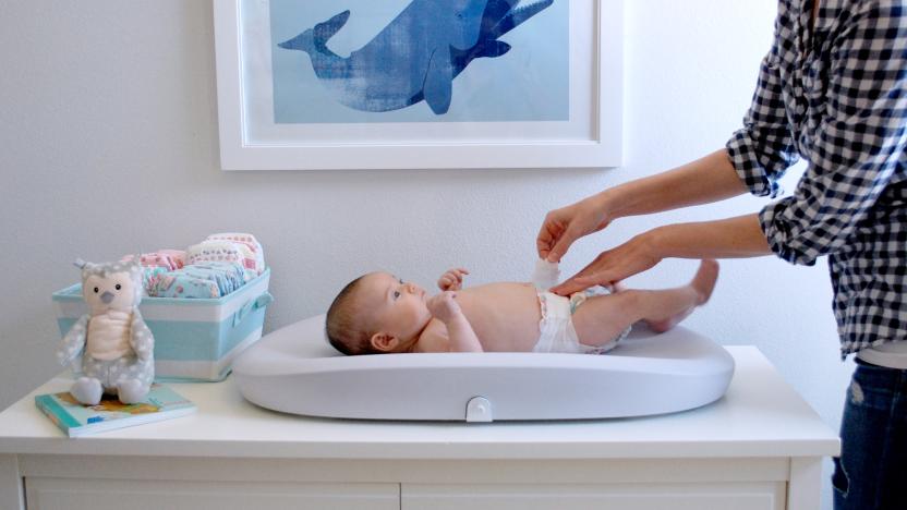 The Hatch Baby Grow changing pad shown in use as a parent changes a baby's diaper.