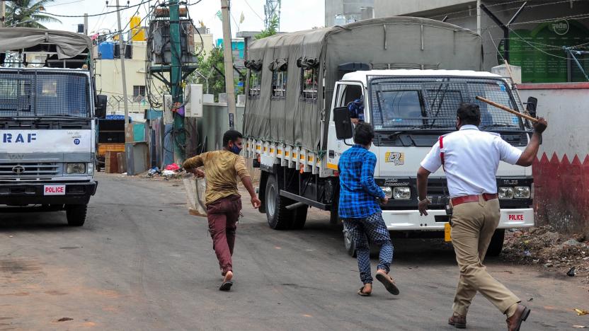 A policeman (R) chases people walking around the clamped area of Devara Jevana Halli in Bangalore on August 13, 2020, after a "derogatory" Facebook post about the Prophet Mohammed sparked riots. - Two people died after a "derogatory" Facebook post about the Prophet Mohammed sparked riots in India's IT hub Bangalore that saw clashes between police and thousands of protesters, authorities said August 12. At least 60 officers were injured the previous evening as a furious crowd attacked a police station, set vehicles on fire and burnt down the house of a local lawmaker whose nephew was allegedly responsible for the social media post. (Photo by Manjunath Kiran / AFP) (Photo by MANJUNATH KIRAN/AFP via Getty Images)