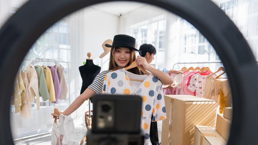 Fashion vlogger presenting dress to cellphone and showing clothes selling online live streaming