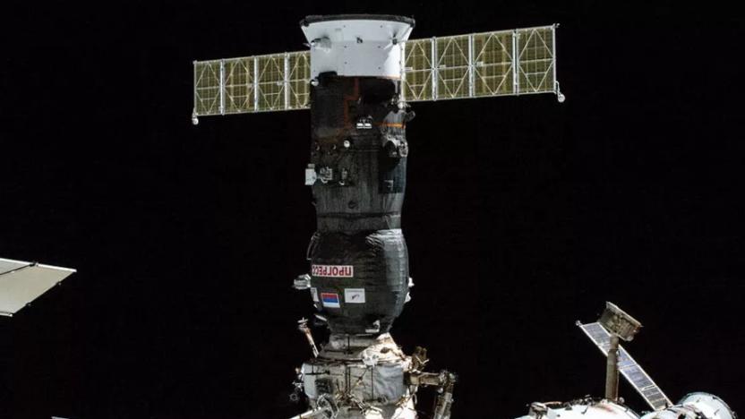 Image of a Russian Progress supply craft docked with the International Space Station, with the black of space in the background.