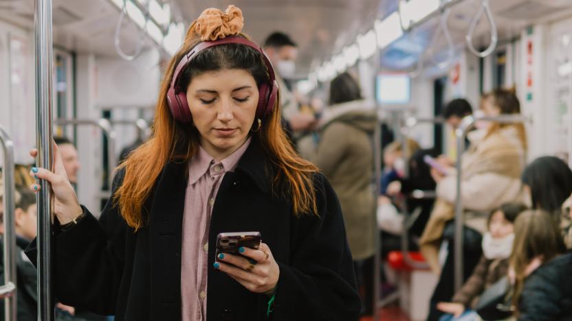 Portrait of young woman in subway listening to music in headphones and using smart phone